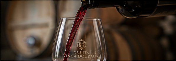 Vinho tinto a ser servido num copo gravado com o monograma da quinta
